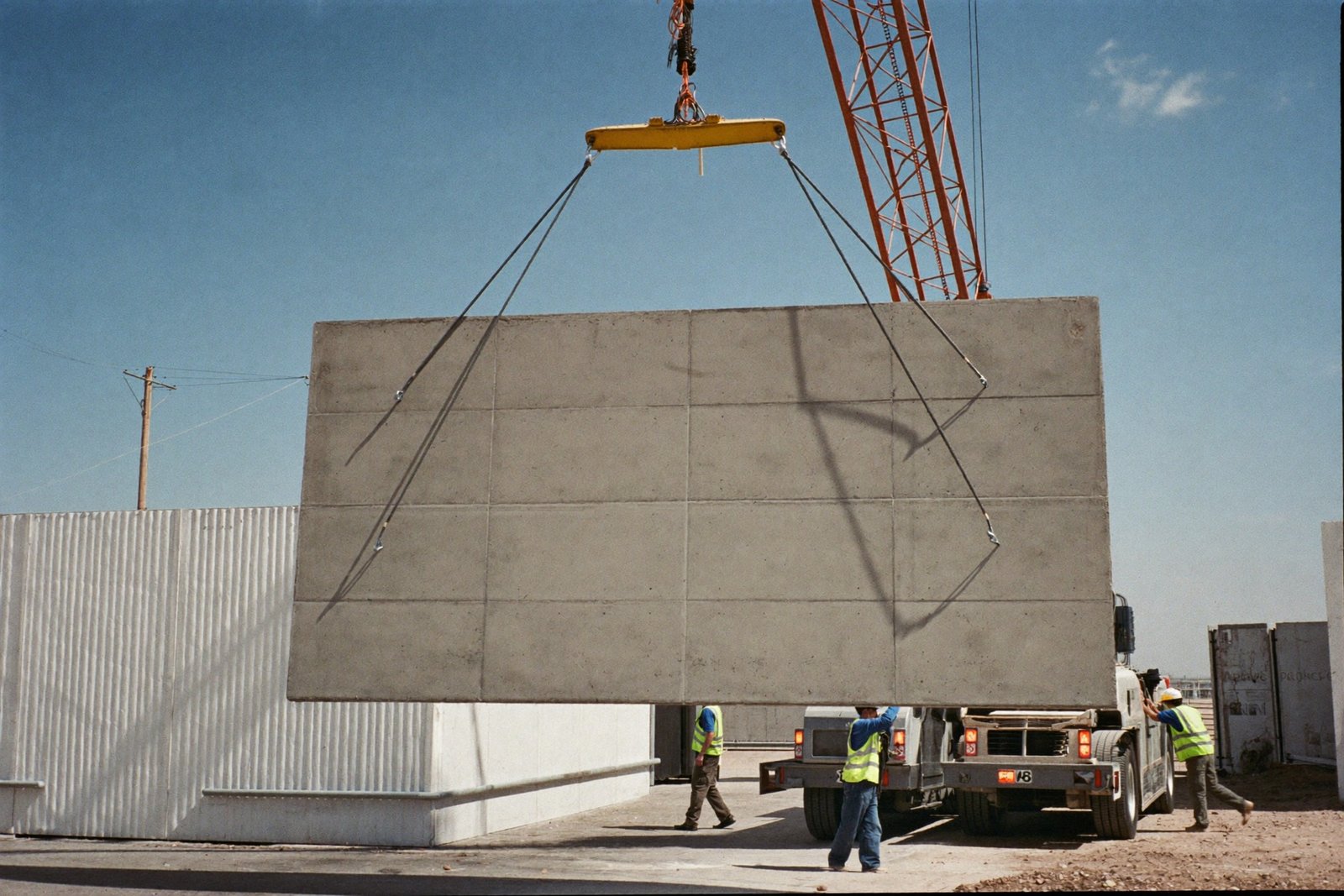 Crane crew bracing a freshly lifted tilt-wall concrete panel in Baytown